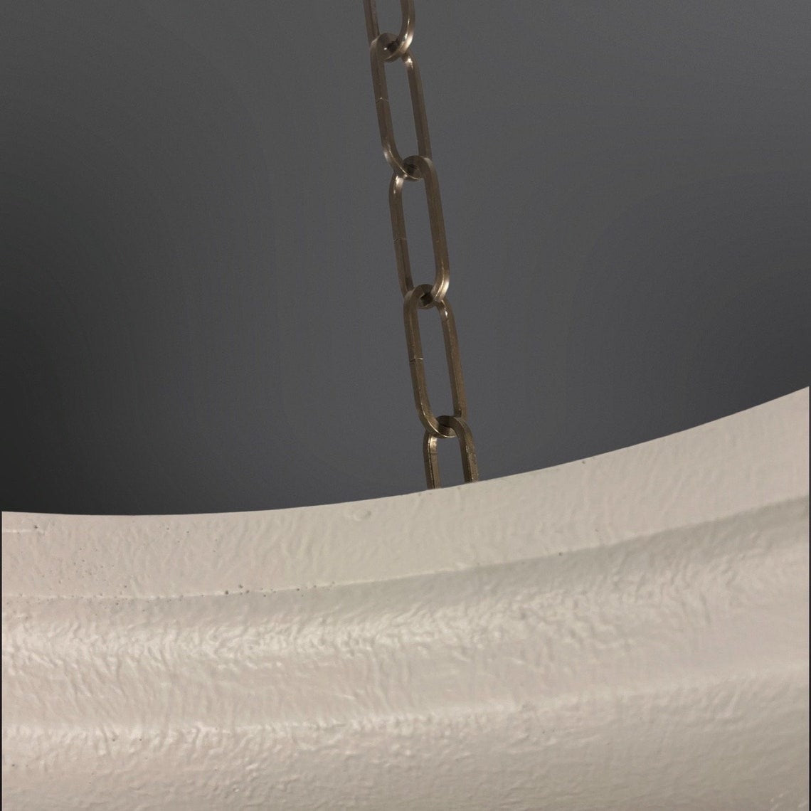 Close-up of a white textured light fixture with a chain.