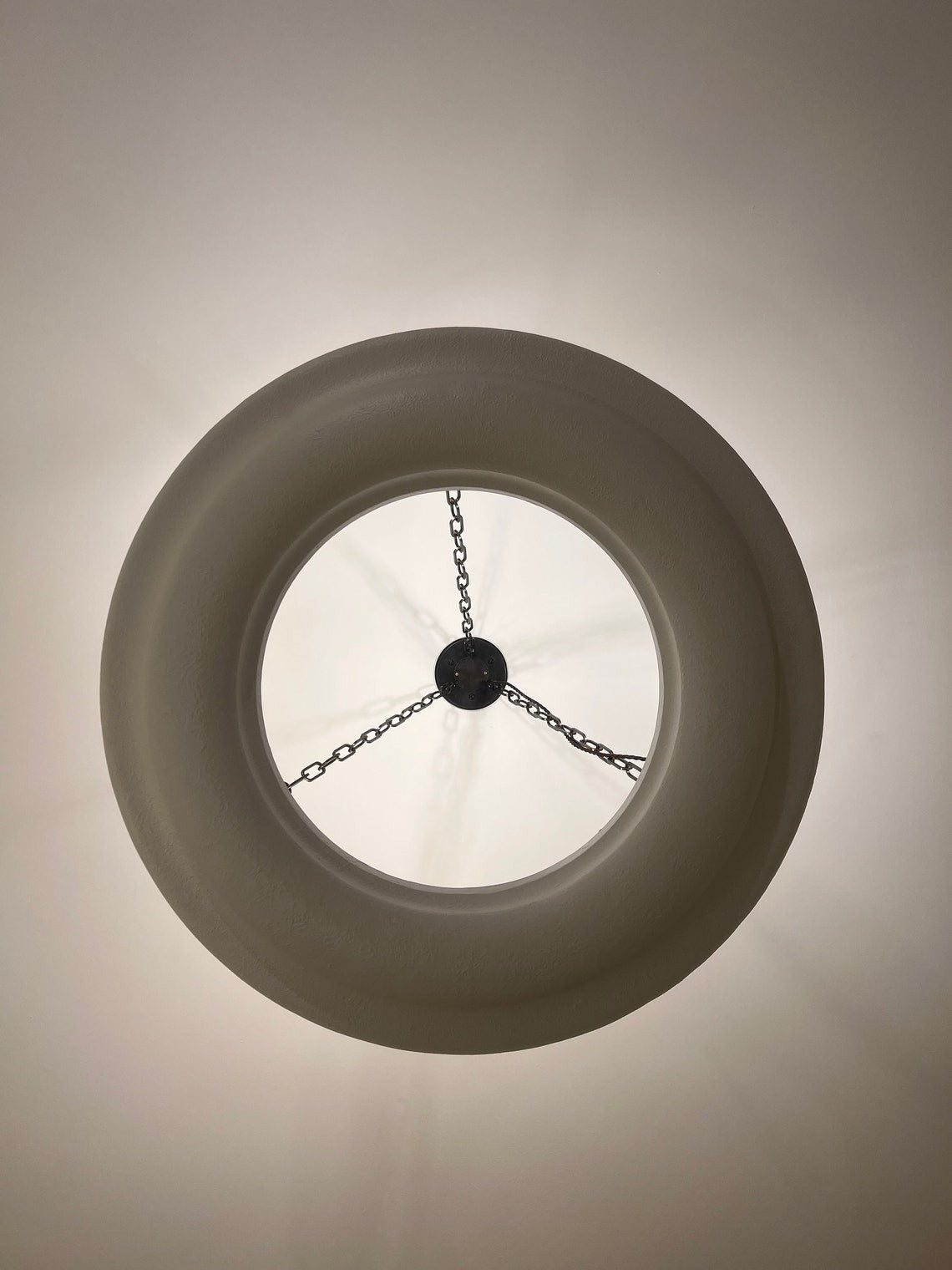 Underside view of a white circular chandelier with chains.