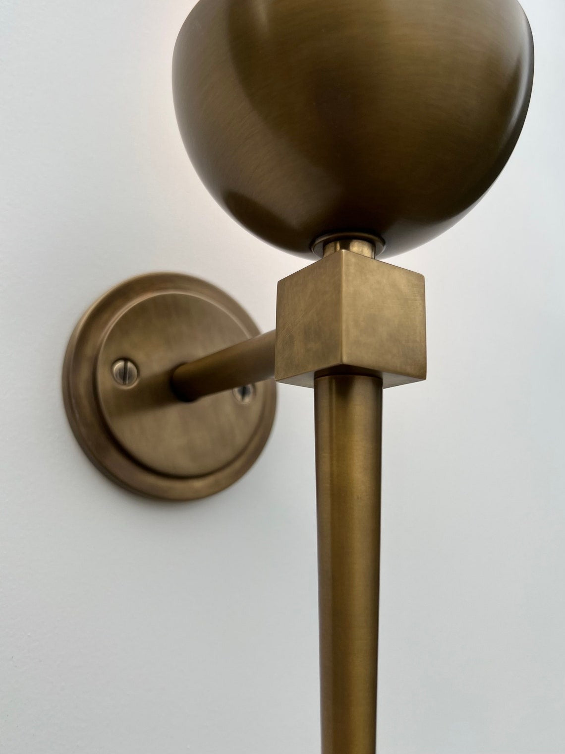 Angled close-up of a brushed brass wall sconce.