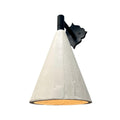 A wall-mounted sconce with a matte black, ornate, scroll-shaped backplate and a short, black arm, holding a downward-facing, textured off-white conical shade. A warm, yellow-orange light glows from the interior of the shade, all set against a plain white background.