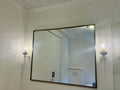 Bathroom with a large mirror flanked by two white wall sconces with clear glass.