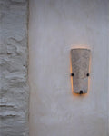 Light-colored stone wall sconce on textured wall.