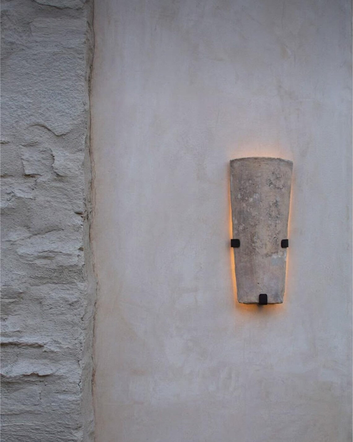 Light-colored stone wall sconce on textured wall.