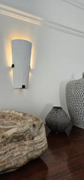 Wall sconce over wooden furniture with decorative vases.