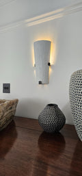 Wall sconce over wooden furniture with decorative vases.