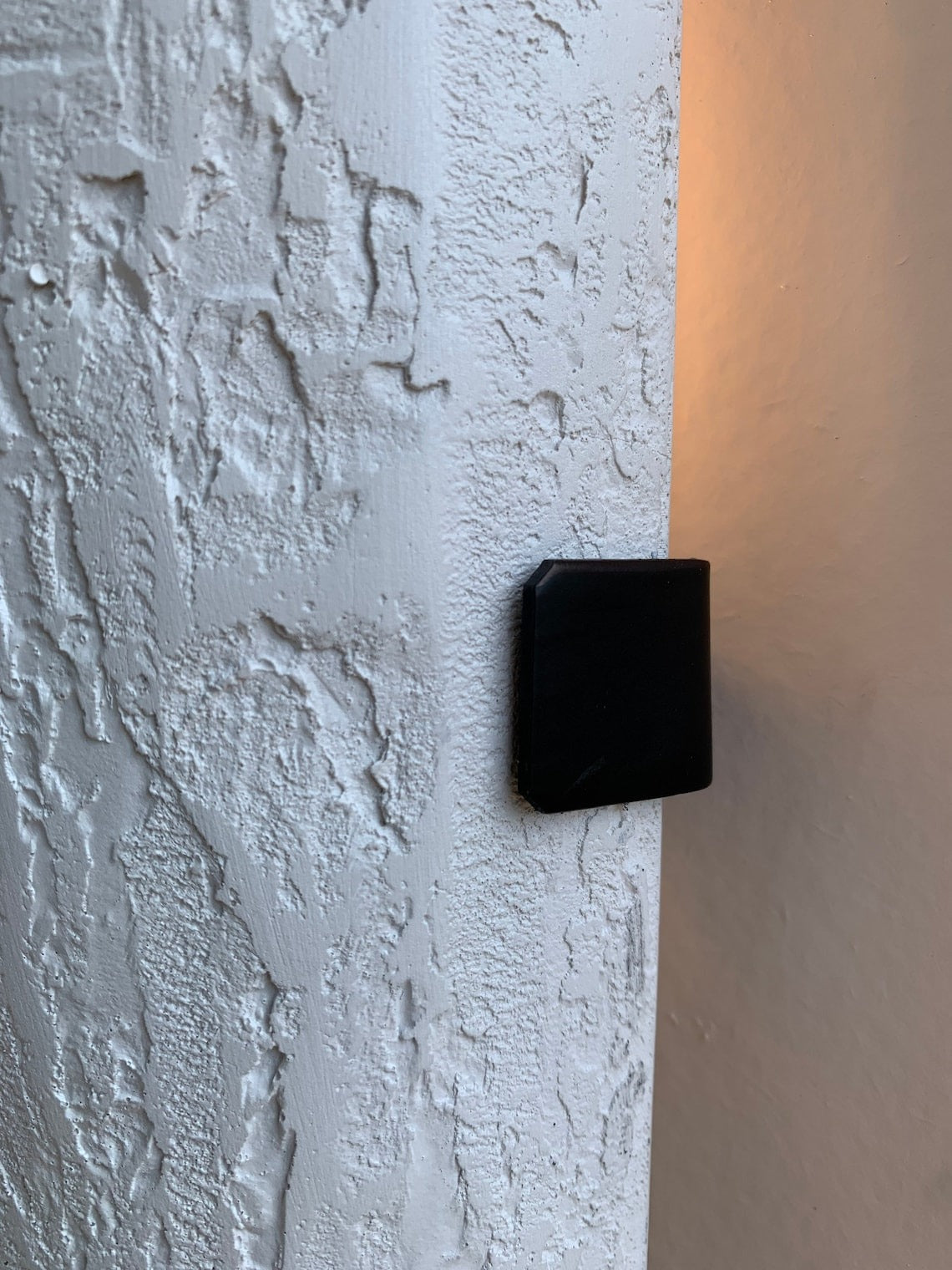 Close-up of textured white sconce with black bracket.