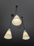 Three conical glass pendant lights with dark chains against a dark background.