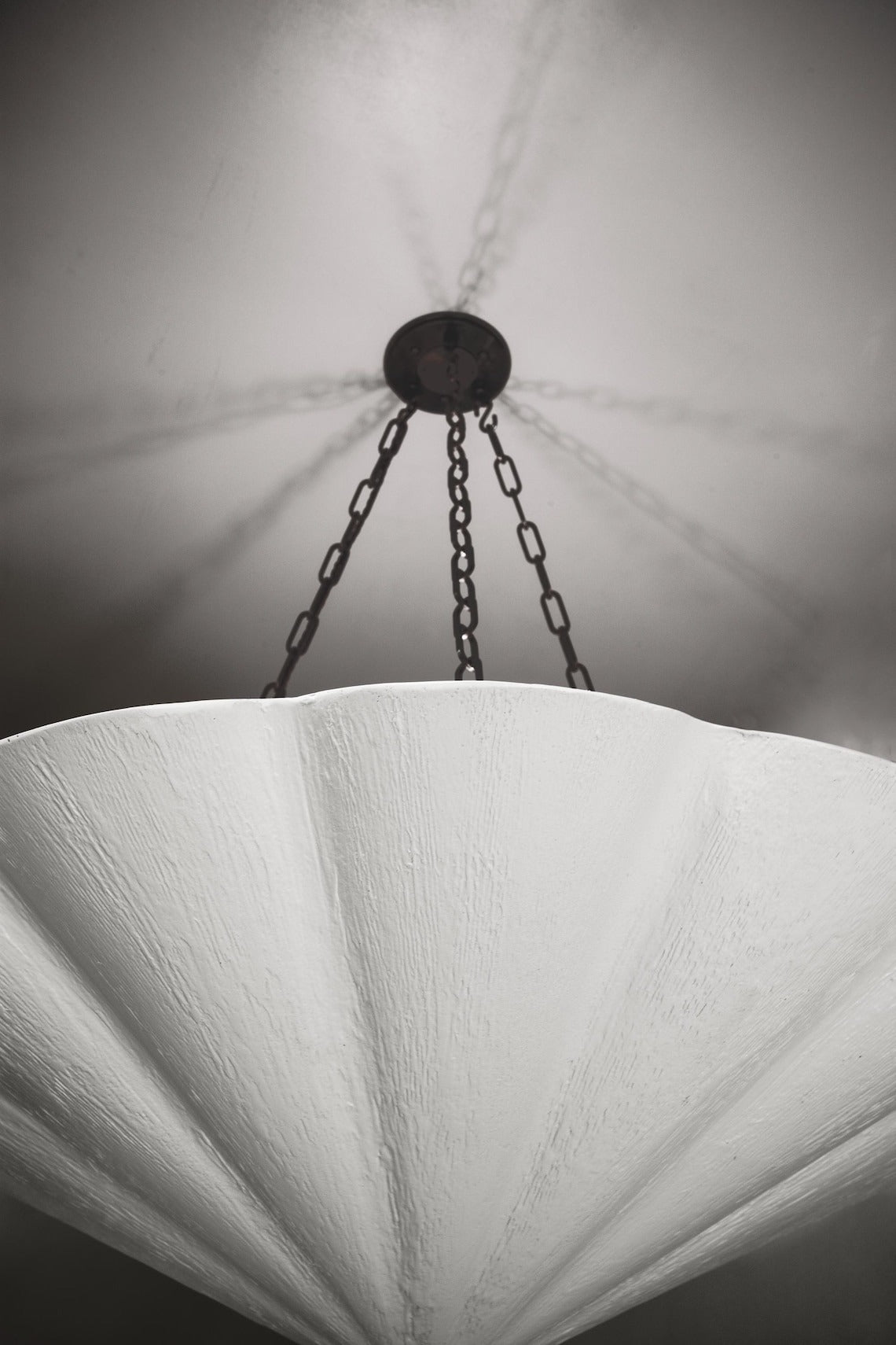 A close-up, low-angle view of a large, white fluted chandelier.