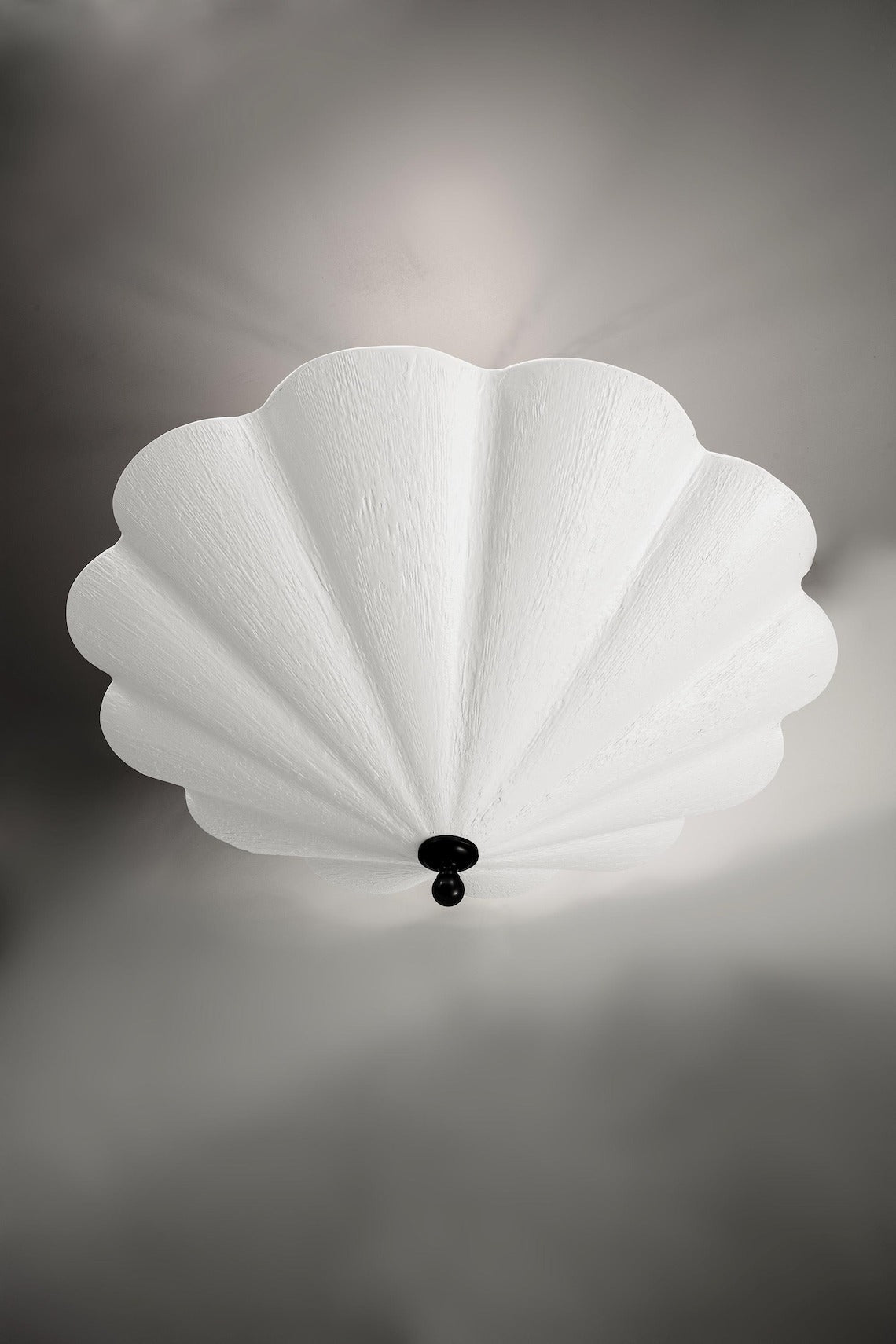 A large, white fluted chandelier hangs from a dark ceiling plate.