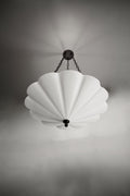 The Small Fluted Pendant Plaster Chandelier, featuring a white, fan-like or fluted plaster shade, suspended by dark metal chains from a matching ceiling mount.