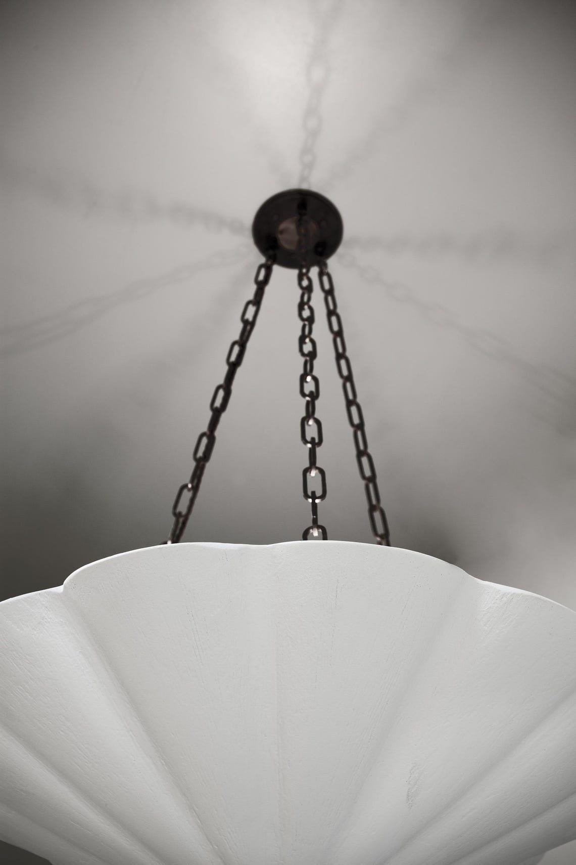 A white fluted pendant chandelier with dark chains.