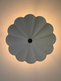 A white, scalloped ceiling light with a dark center, viewed from below.
