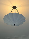 A white scalloped pendant light with a warm glow.