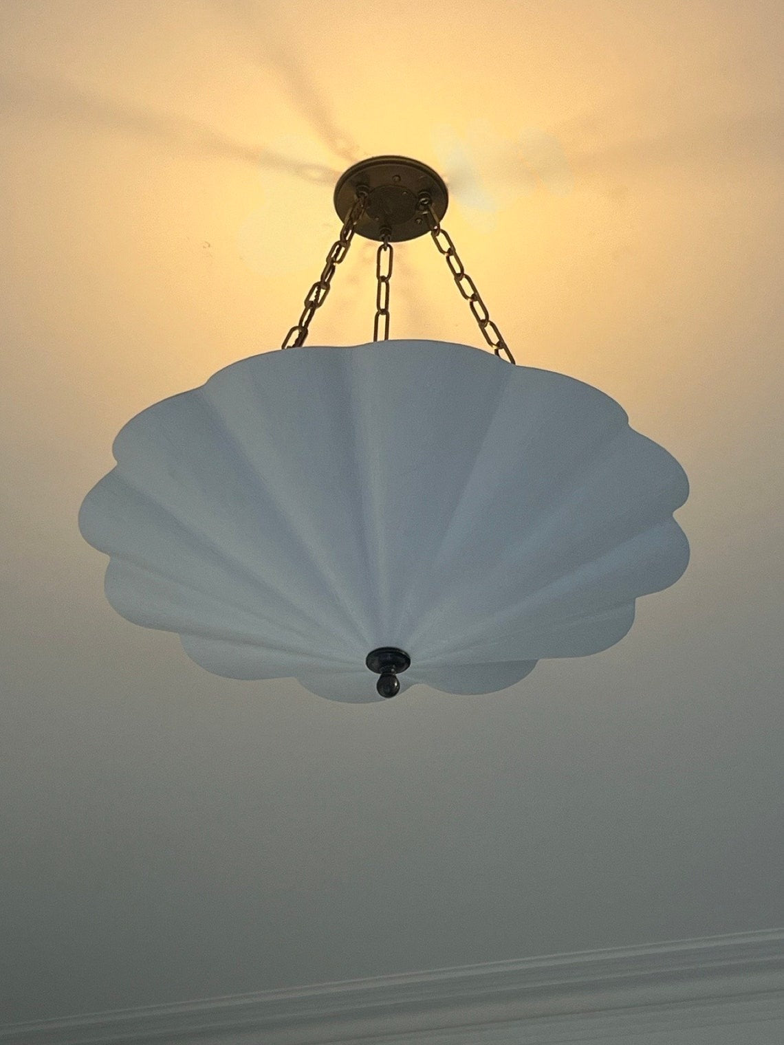 A white scalloped pendant light with a warm glow.