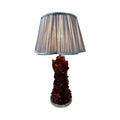 A table lamp with a dark red, textured base and a pleated light-colored shade.