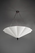 A large, white fluted chandelier hangs from a dark ceiling plate by chains.