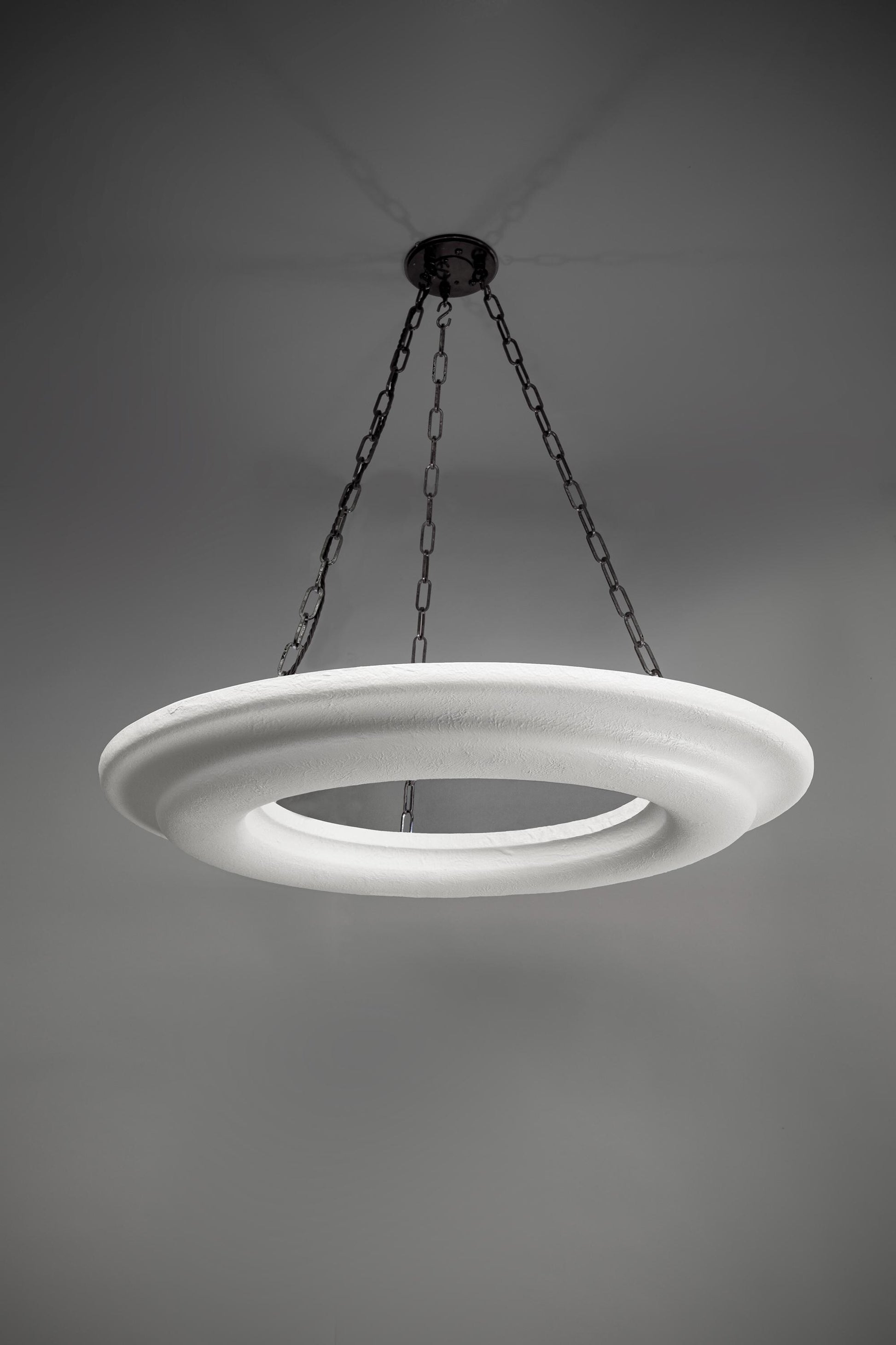 White circular pendant light with a textured surface, suspended by chains.