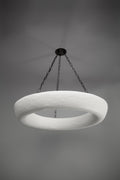 A white, textured circular chandelier hangs from a dark ceiling plate by chains.