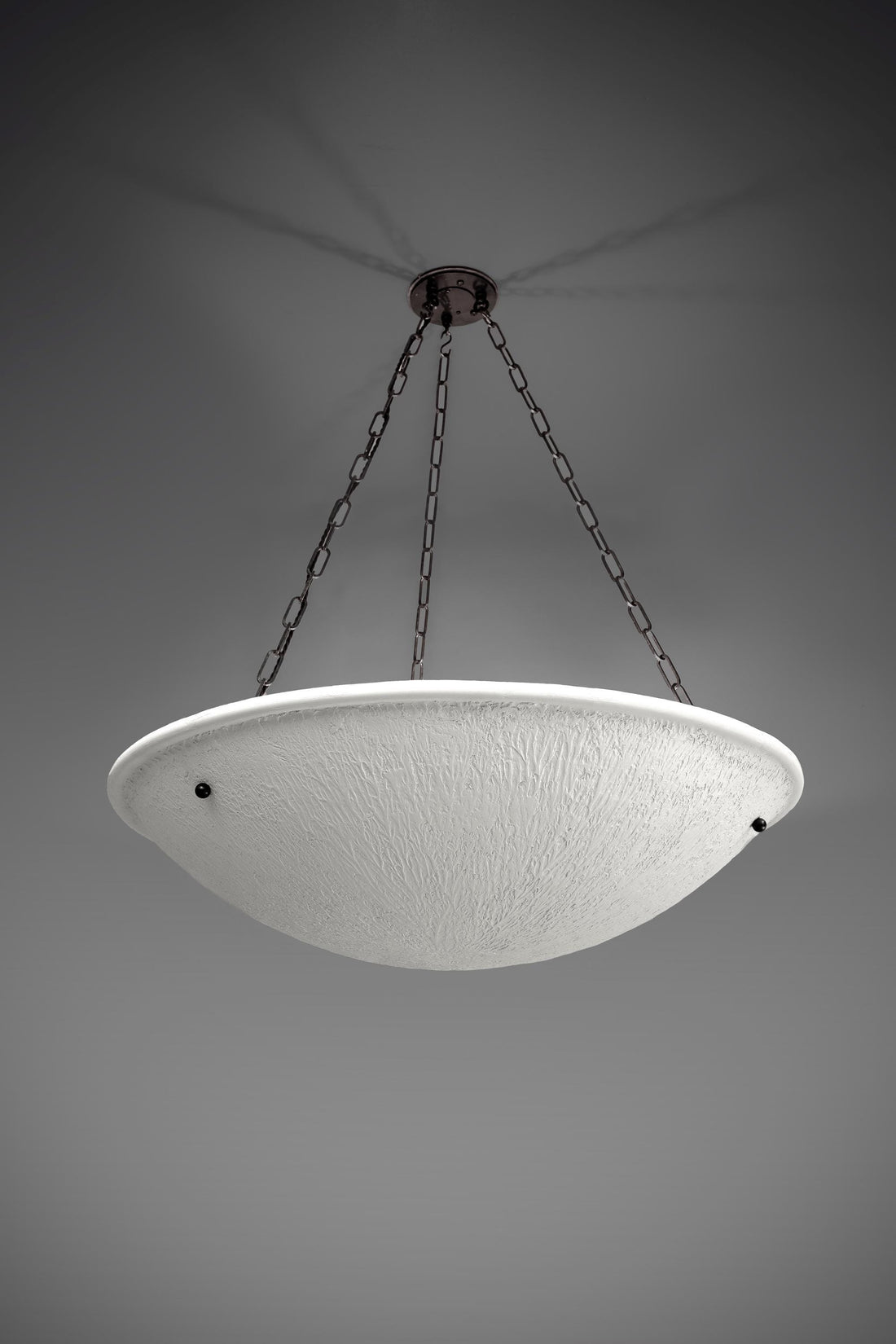 A large Neo-Classical style chandelier featuring a wide, shallow dish-shaped white plaster shade with a textured surface. It is suspended by three dark metal chains from a dark ceiling mount, casting subtle shadows.