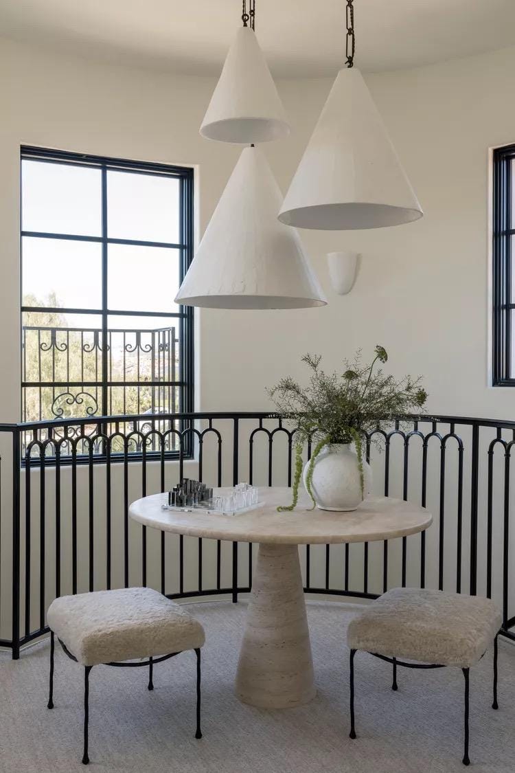 A modern landing with 22-Inch large handmade plaster cone pendant lights, a round table, and two stools.